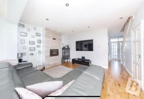 a living room with a gray couch and a television at End of Terrace 4 bedroom 2 living room home in London in Harold Wood