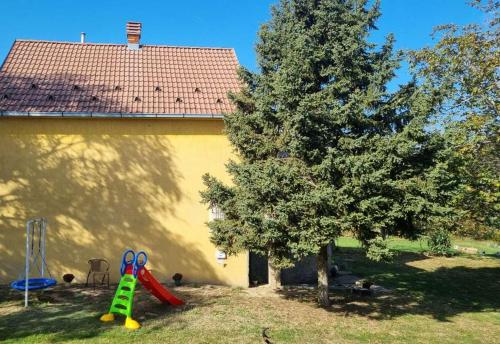 a tree and playground equipment in front of a house at Casa Horizont in Slankamenački Vinogradi