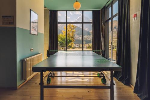 a ping pong table in a room with a window at Intourist Kazbegi in Stepantsminda