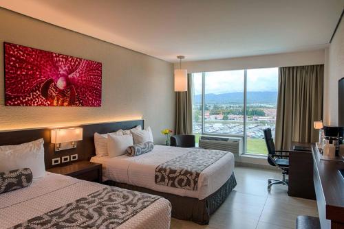 a hotel room with two beds and a large window at Crowne Plaza Airport by IHG in Tocumen