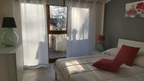 a bedroom with a bed with red pillows and a window at La Limonaia Country House in Monteriggioni