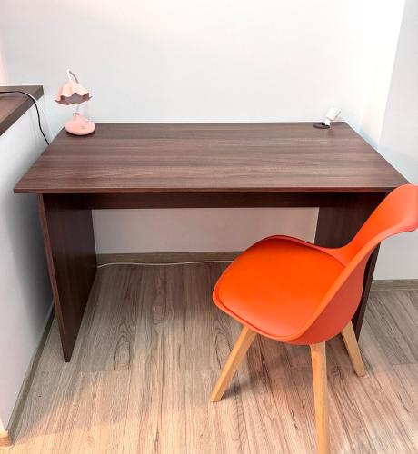 a wooden desk with a orange chair next to it at CRISTAL Home Boutique Apartment 1 - Confort, Spatios, Linistit, Zona de interes in Craiova