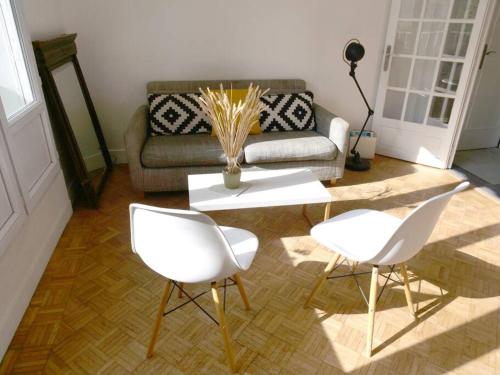 un salon avec deux chaises blanches et une table dans l'établissement Appartement de designer, Grand Paris pour 6 personnes, Metro 14, au Kremlin-Bicêtre