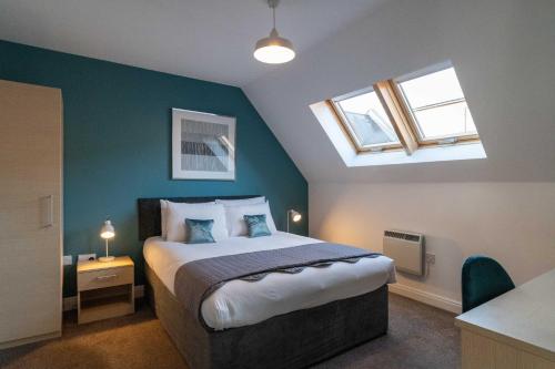 a bedroom with a bed with a blue wall at Cotels - The Millhouse NEWLY REFURBISHED MODERN APARTMENTS WITH ULTRAFAST BROADBAND, FREE PARKING & A WORK DESK in Derby