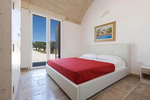 una camera da letto bianca con un letto con una coperta rossa di La Serrazza by BarbarHouse a Marina di Pescoluse