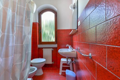 Baño rojo con aseo y lavamanos en Casa Palmaiola, en Cavo