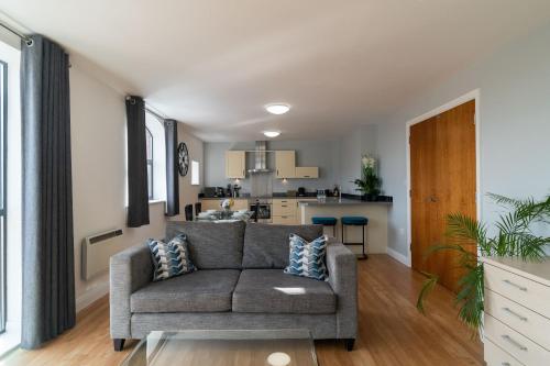 a living room with a couch and a kitchen at Cotels - The Millhouse NEWLY REFURBISHED MODERN APARTMENTS WITH ULTRAFAST BROADBAND, FREE PARKING & A WORK DESK in Derby