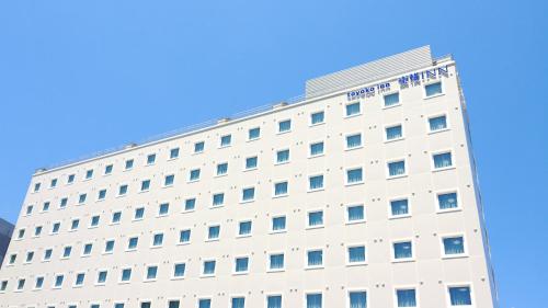 a white hotel building with a blue sky in the background at Toyoko Inn Chigasaki Shiyakusho in Chigasaki