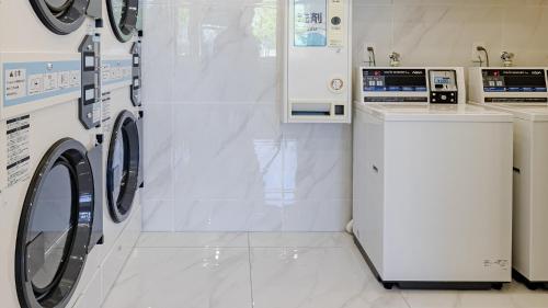 a white laundry room with two washers and a counter at Toyoko Inn Chigasaki Shiyakusho in Chigasaki