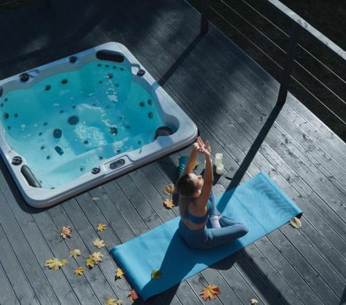 a woman sitting on a yoga mat next to a pool at Rezydencja Bieszczady - Solina in Solina
