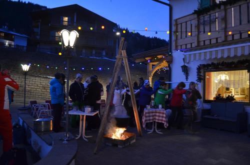 a group of people standing outside a restaurant at night at Latemar - Hotel Suites Spa in Soraga