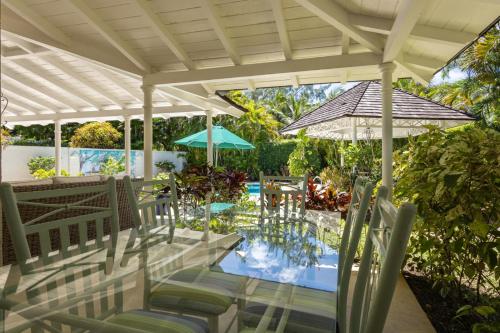 a patio with chairs and an umbrella and a pool at Lonetrees - Large Luxury Private Villa w Pool in Saint James
