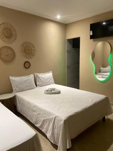 a bedroom with a large white bed with a mirror at Pousada jardim imbassay in Mata de Sao Joao