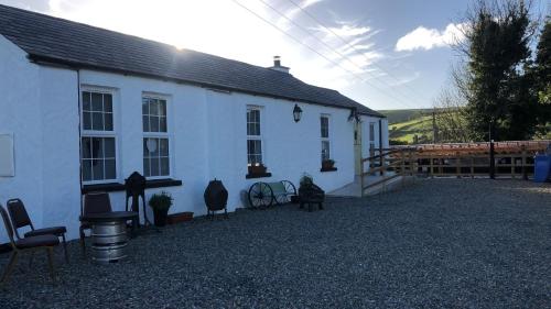 a white house with some chairs in front of it at Terry Joe Cottages in Newry