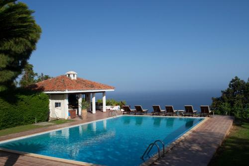 a swimming pool with chairs and a house at Villas La Gomera in Alajeró