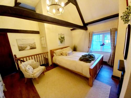 a bedroom with a bed and a chair and a window at Yewtree Cottage in Strensall