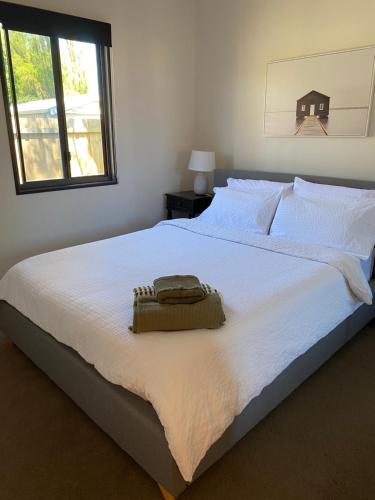 - un grand lit blanc avec un sac dans l'établissement Serenity Cottage Wonthaggi, à North Wonthaggi