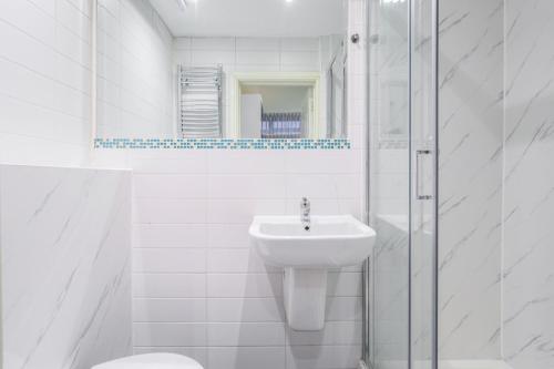 uma casa de banho branca com um lavatório e um chuveiro em Chic Stay in London em Londres