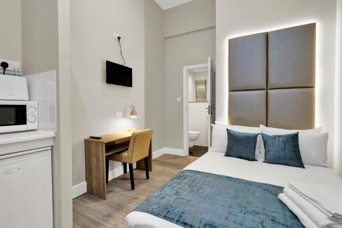 um quarto com uma cama, uma secretária e um micro-ondas em Chic Stay in London em Londres