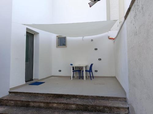ein weißes Zimmer mit einem Tisch und einem blauen Stuhl in der Unterkunft Villa Belvedere Salento in Porto Cesareo