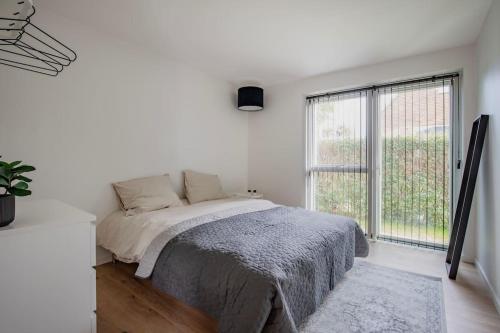 biała sypialnia z łóżkiem i dużym oknem w obiekcie Spacious family house w Kopenhadze