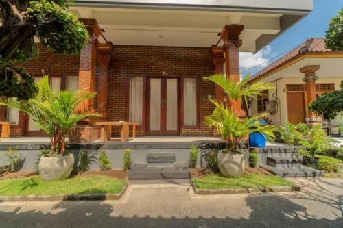 a house with palm trees in front of it at Pondok Lulik Homestay Canggu in Canggu