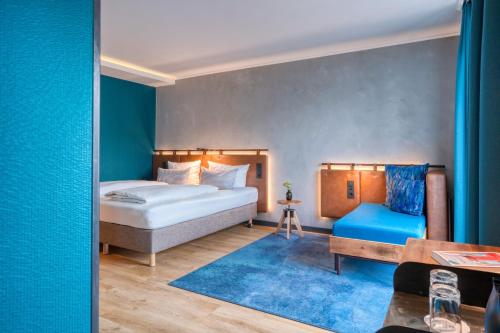 ein Schlafzimmer mit einem Bett und einer blauen Wand in der Unterkunft Unsöld's Factory Hotel in München