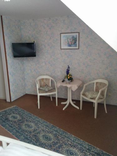 a room with two chairs and a table and a tv at Hotel Seemöwe in Simmerath