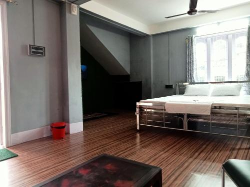 een slaapkamer met een bed en een houten vloer bij Ellys home stay in Guwahati