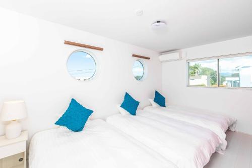 two beds in a white room with blue pillows at Nanki Shirahama Venus in Shirahama