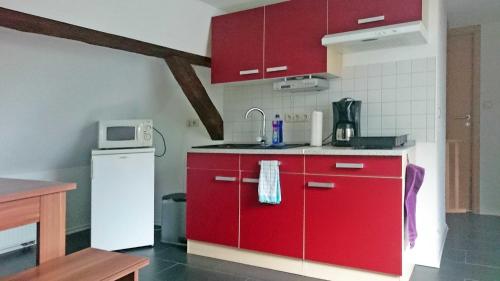 eine Küche mit roten Schränken und einem weißen Kühlschrank in der Unterkunft Ferienwohnung im Wiesengrund in Stahlbrode