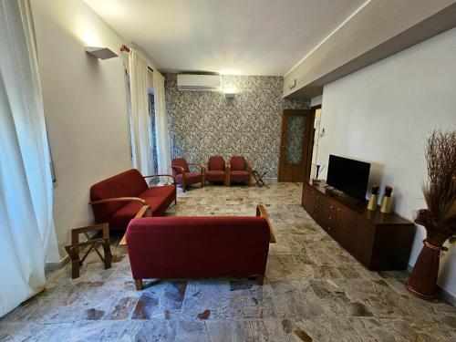 a living room with red chairs and a television at La Casa di Nazareth in Rome