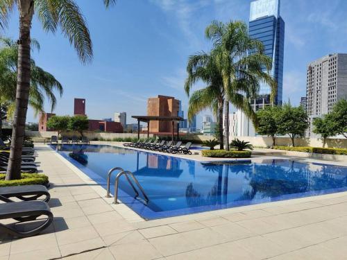 basen z krzesłami i palmami w mieście w obiekcie Penthouse liu east piso 35 valle oriente w mieście Monterrey