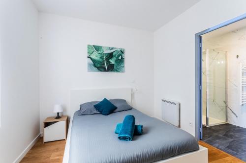 sypialnia z łóżkiem z niebieskimi poduszkami w obiekcie Le Musée 1, Cosy 2 pièces w mieście Bergerac