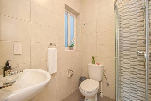 Baño blanco con aseo y lavamanos en Sea View Suite!, en Marsalforn