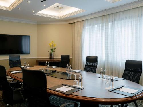 une salle de conférence avec une grande table et des chaises en bois dans l'établissement Grand Mercure Sao Paulo Ibirapuera, à São Paulo