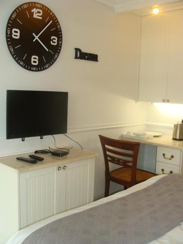 ein Schlafzimmer mit einer Uhr an der Wand und einem Schreibtisch mit einem Stuhl in der Unterkunft Lonehill - Standard 2 Guest Studio Suite 1 in Sandton