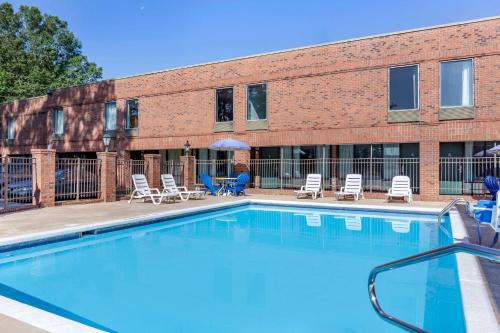a swimming pool in front of a brick building at Days Inn & Suites by Wyndham Rocky Mount Golden East in Rocky Mount