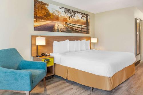 a bedroom with a bed and a blue chair at Days Inn & Suites by Wyndham Rocky Mount Golden East in Rocky Mount