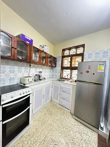 a kitchen with white cabinets and a stainless steel refrigerator at Yahya Apartments in Ngambo