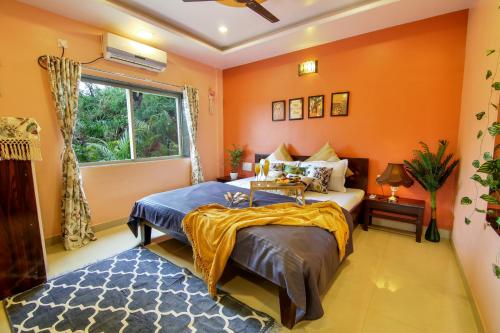 a bedroom with orange walls and a bed and a window at Elsewhere Villa by Hill Staytion in Mahabaleshwar