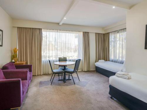 a hotel room with a bed and a table and chairs at Mercure North Melbourne in Melbourne