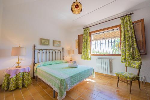 a bedroom with a bed and a chair and a window at Villa Mas Blanc - PlusHolidays in Benissa