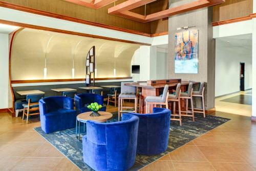 a lobby with blue chairs and tables and a bar at Hyatt Place Louisville-East in Louisville