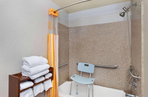a bathroom with a shower and a toilet and a chair at La Quinta by Wyndham Bowling Green in Bowling Green