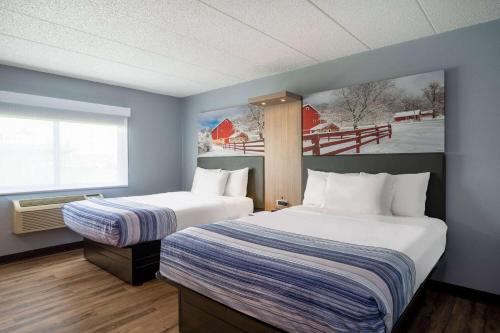 a hotel room with two beds and a window at AmericInn by Wyndham Eau Claire in Eau Claire