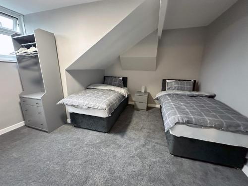 a bedroom with two beds and a staircase at Modernised 3 Bedroom House, Lascelle Residence in Roundhay