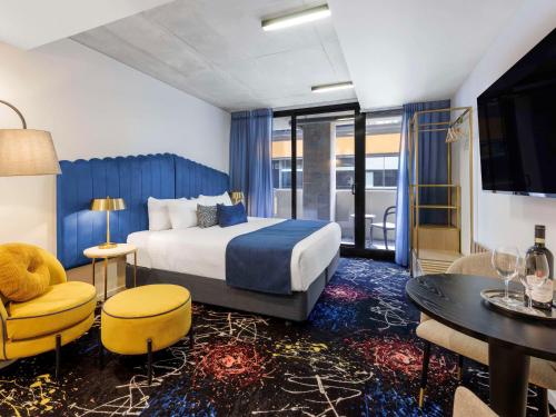 a hotel room with a bed and a table and chairs at Mercure Melbourne St Kilda Road in Melbourne