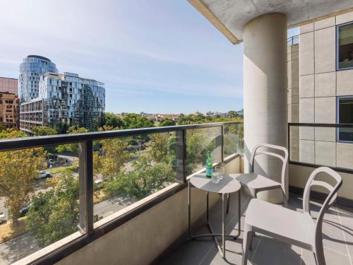 einen Balkon mit einem Tisch und Stühlen sowie Stadtblick in der Unterkunft Mercure Melbourne St Kilda Road in Melbourne