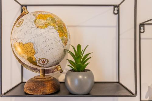 a globe on a shelf next to a potted plant at Le Musée 2, Industriel 2 pièces in Bergerac